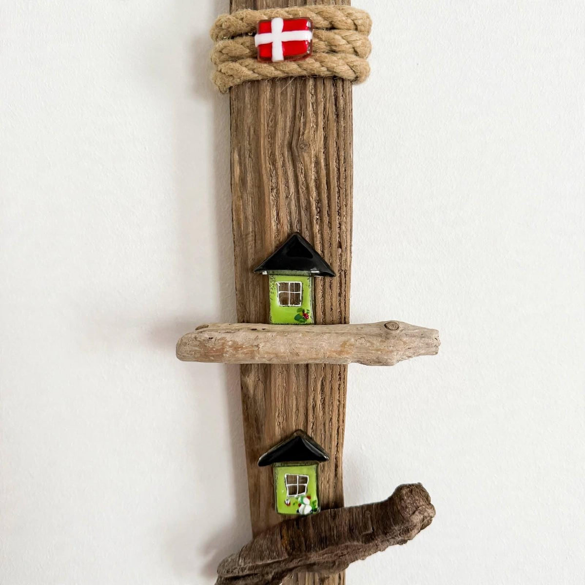 Oberes grünes Häuschen mit Dänemark Flagge darüber auf Treibholz Detail