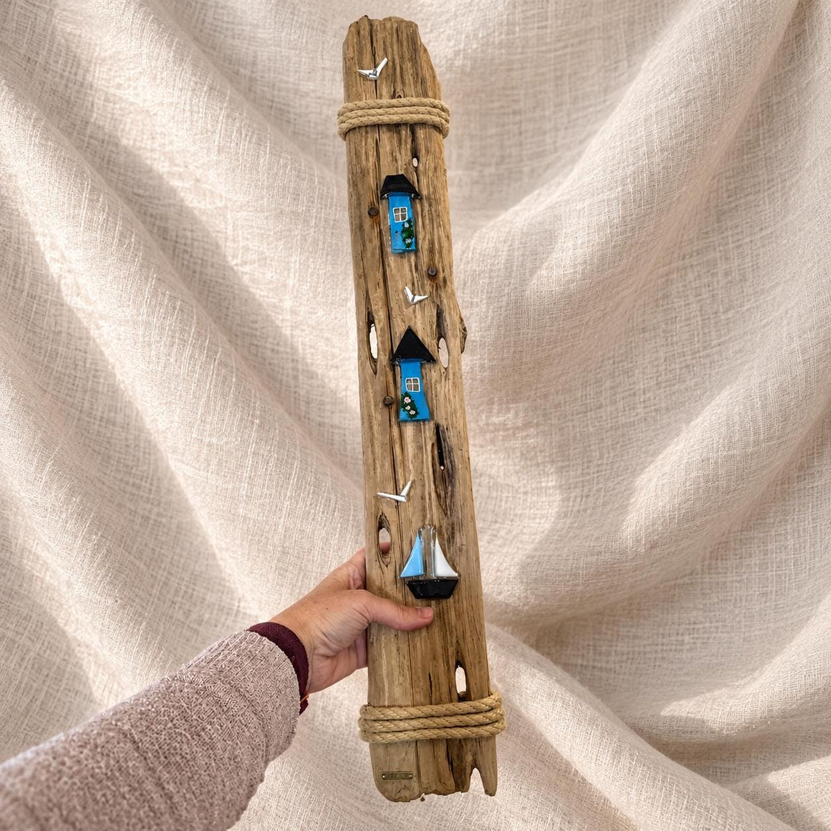 Schmales Treibholzbild 37 x 10cm in Hand gehalten - 2 blaue Glashäuser und Segelboot aus Glas auf hohem Treibholz mit Jute