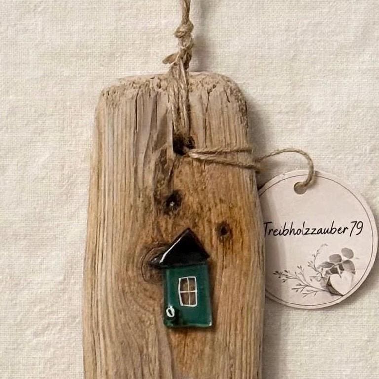 Detail Treibholzbrett mit einem dunkelgrünen Fusing Glas Haus mit schwarzem Dach und Jute Aufhängung, skandinavische Wanddeko