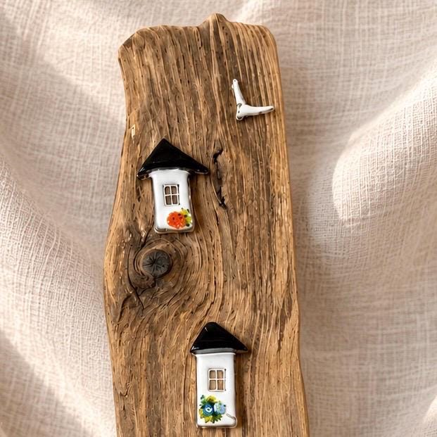 Detail oben Treibholzbild - zwei kleine weiße Glashäuser mit schwarzen Dächern und weiße Möwe auf verwittertem Treibholz